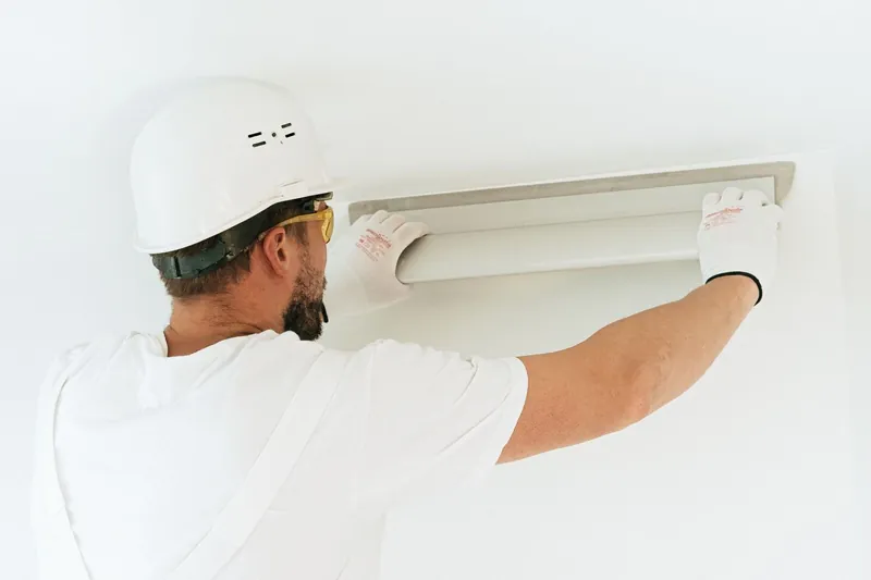 Electrician installing a chandelier fixture on a high ceiling