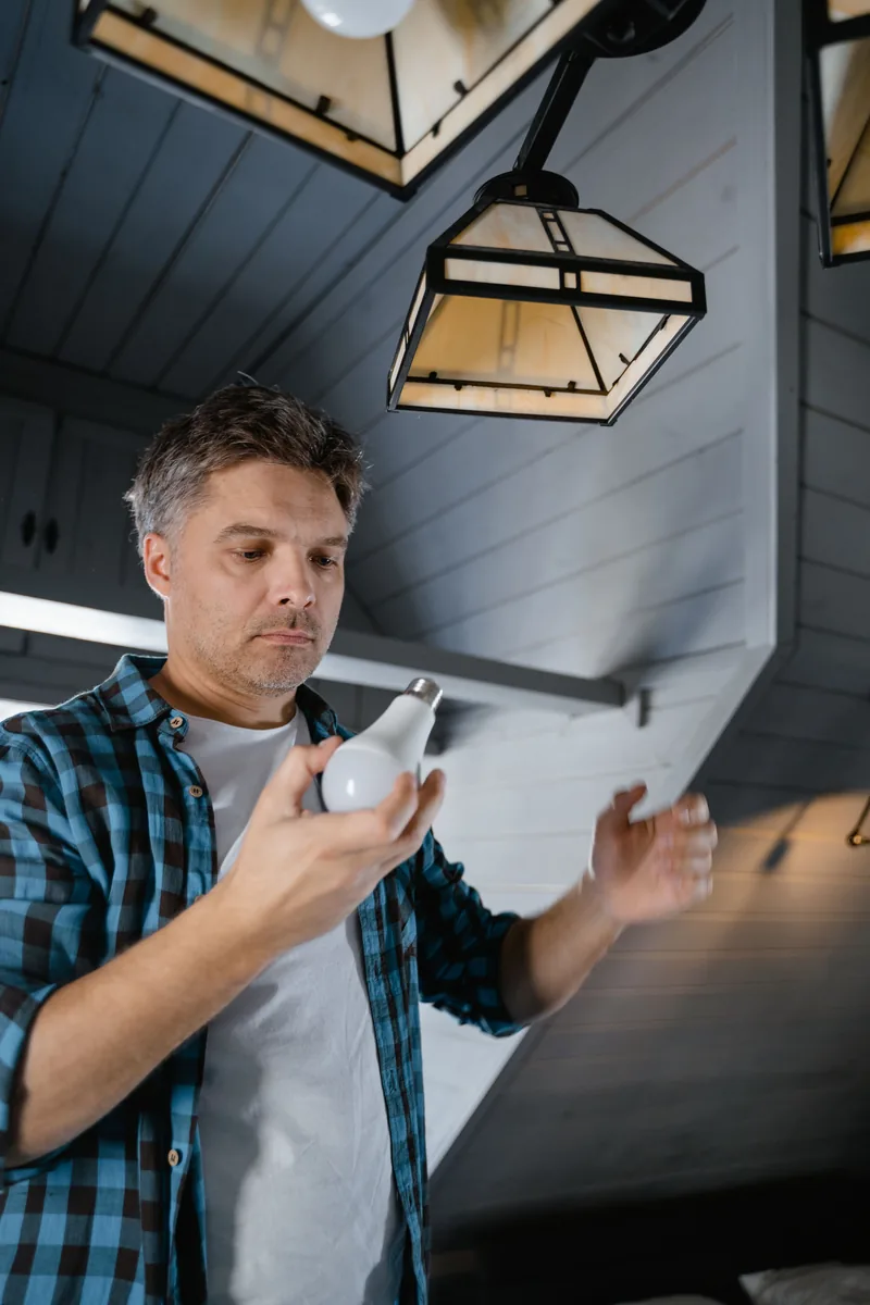 Electrician installing a modern ceiling light fixture with a drill