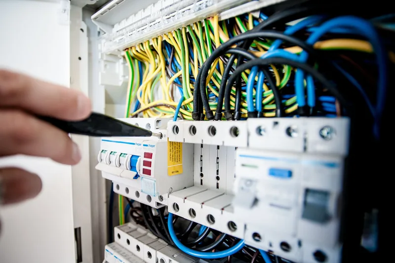 Electrician tightening breaker connections inside an open residential electrical panel