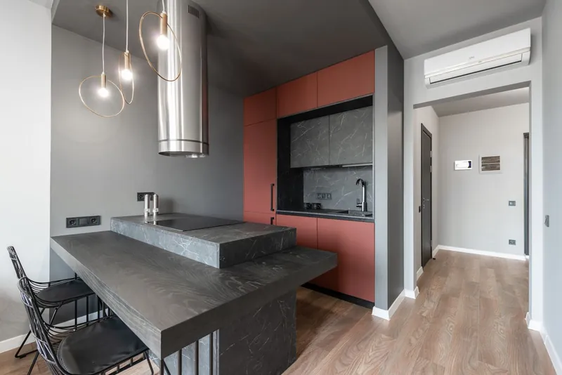 Modern kitchen island lit by hanging pendant lights